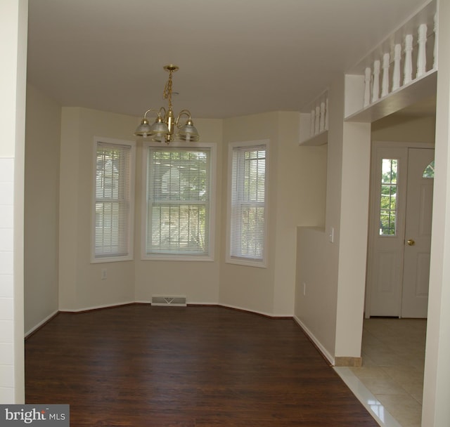 unfurnished dining area with dark hardwood / wood-style flooring and a notable chandelier