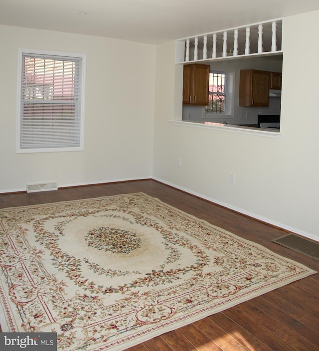 spare room featuring plenty of natural light and dark hardwood / wood-style flooring