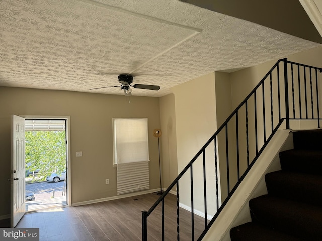 stairway featuring a textured ceiling, ceiling fan, and hardwood / wood-style flooring