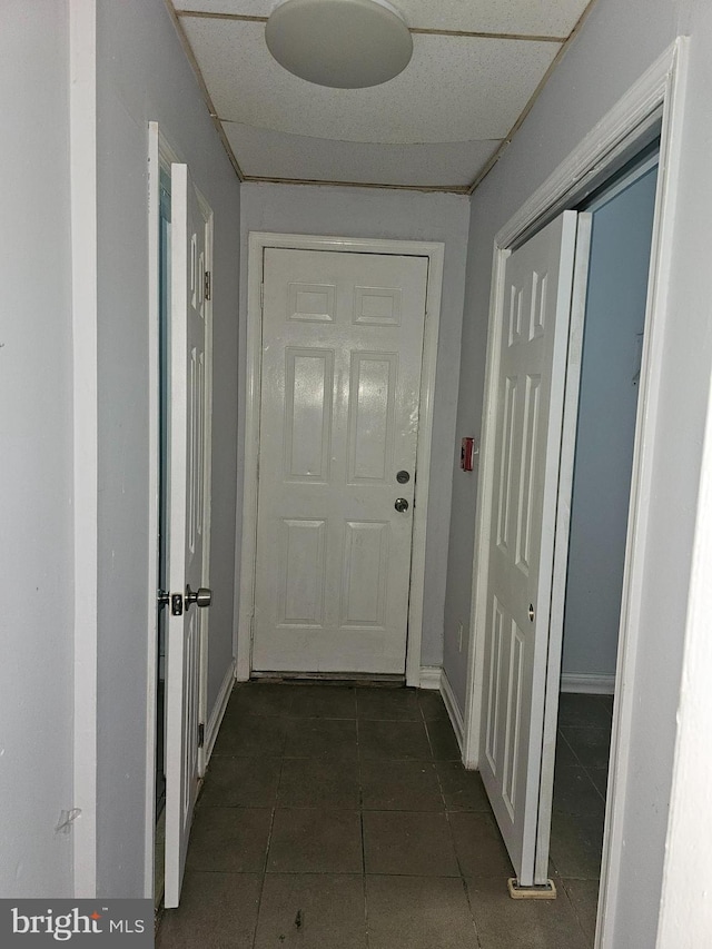 corridor featuring a drop ceiling and dark tile patterned flooring