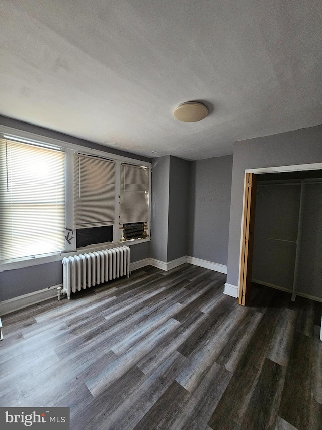 unfurnished living room with radiator, a textured ceiling, and dark hardwood / wood-style floors