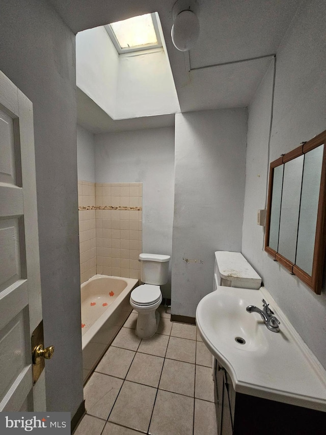 bathroom with a skylight, a washtub, toilet, tile patterned floors, and vanity