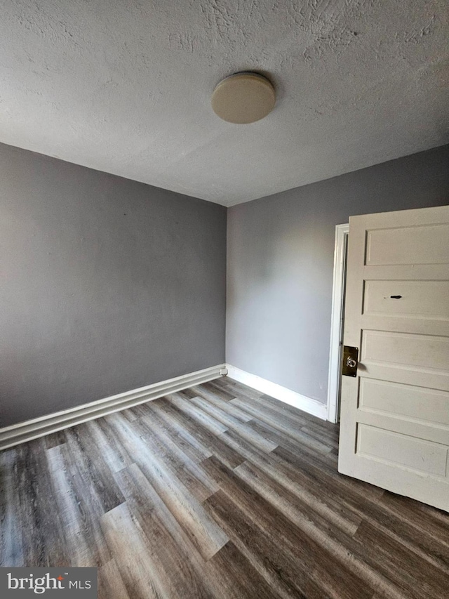 empty room with dark wood-type flooring and a textured ceiling