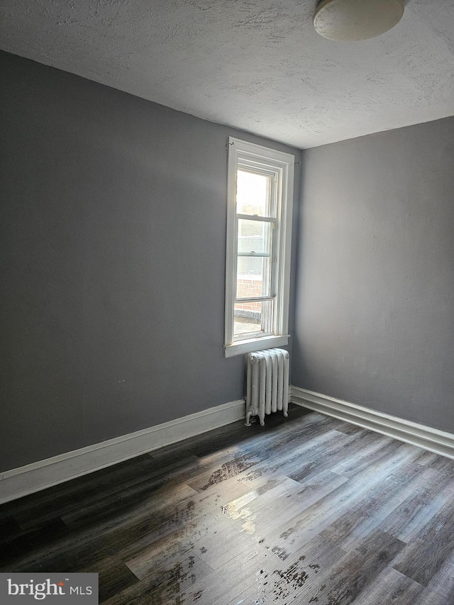 unfurnished room featuring radiator heating unit, a textured ceiling, and dark hardwood / wood-style flooring