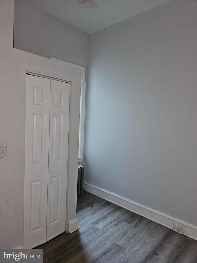 unfurnished bedroom featuring dark wood-type flooring and a closet