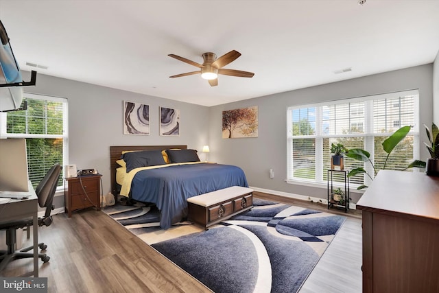 bedroom with multiple windows, ceiling fan, and light hardwood / wood-style flooring