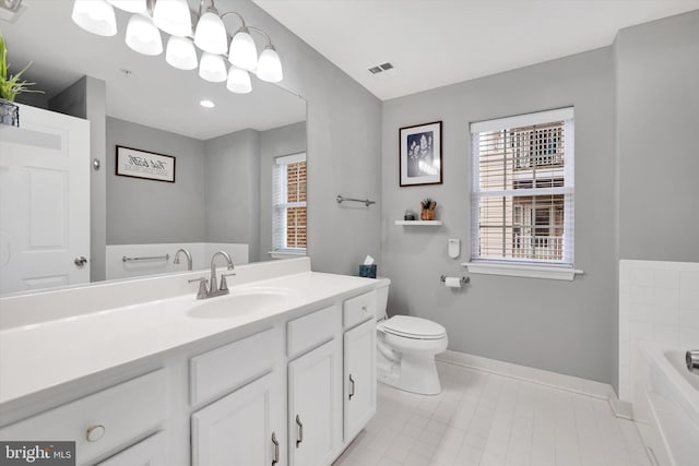 bathroom with tile patterned flooring, a washtub, vanity, and toilet