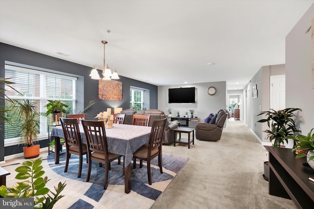 carpeted dining area featuring a notable chandelier