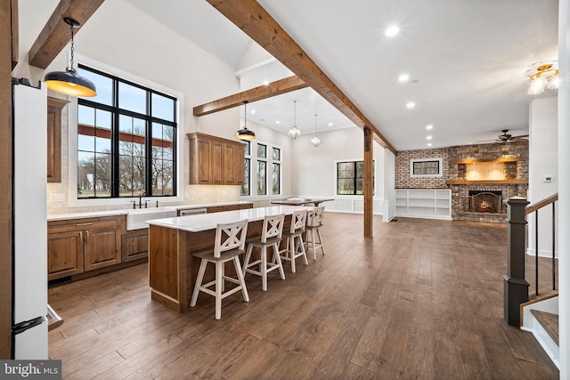 kitchen featuring dark wood-type flooring, hanging light fixtures, a kitchen island, and a fireplace