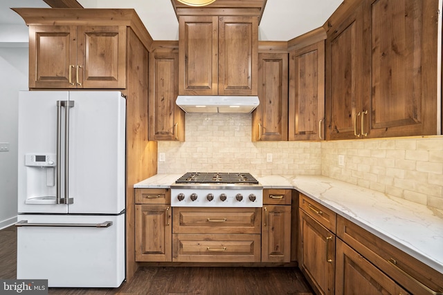 kitchen featuring stainless steel gas cooktop, high end white fridge, decorative backsplash, light stone countertops, and dark wood-type flooring