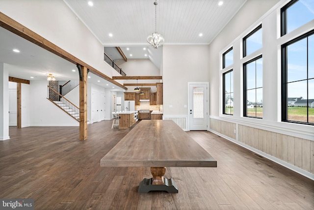 exercise room with a high ceiling, wood walls, a chandelier, and dark hardwood / wood-style flooring