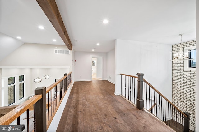 hall with beamed ceiling, hardwood / wood-style floors, and a notable chandelier