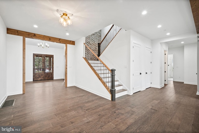 foyer entrance with a notable chandelier, dark hardwood / wood-style floors, and beam ceiling