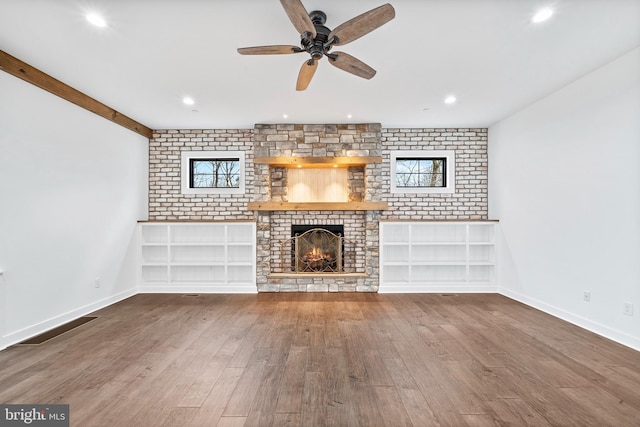 unfurnished living room featuring ceiling fan, hardwood / wood-style flooring, a fireplace, and brick wall