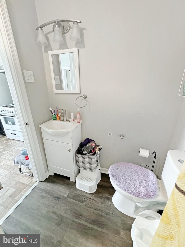 bathroom with wood-type flooring, vanity, and toilet