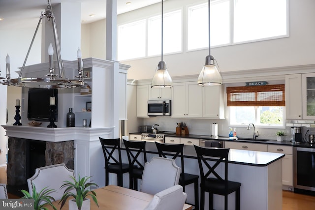 kitchen featuring appliances with stainless steel finishes, white cabinetry, a breakfast bar area, pendant lighting, and sink