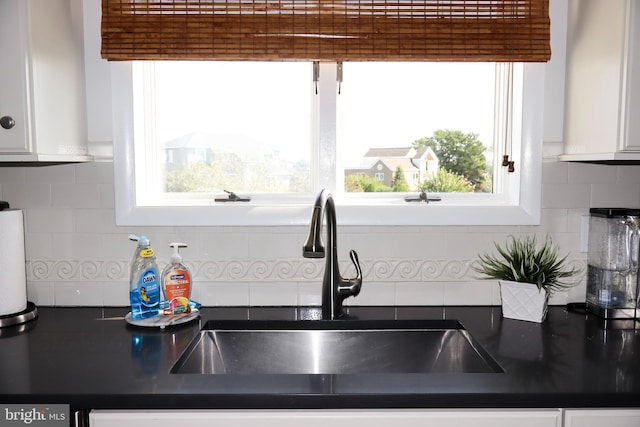 kitchen with decorative backsplash, a wealth of natural light, white cabinets, and sink