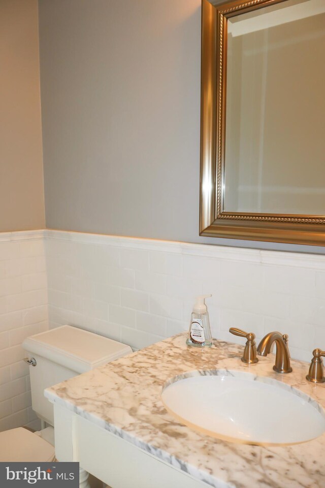 bathroom with vanity, tile walls, and toilet