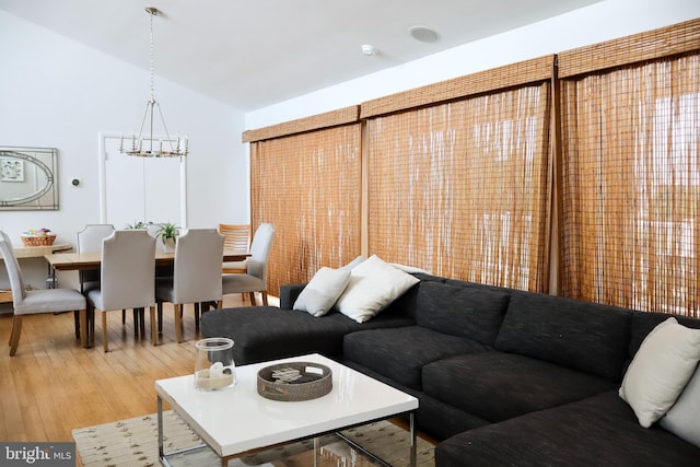 living room with vaulted ceiling, an inviting chandelier, and hardwood / wood-style floors