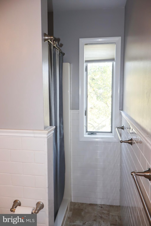 bathroom featuring tile walls and curtained shower