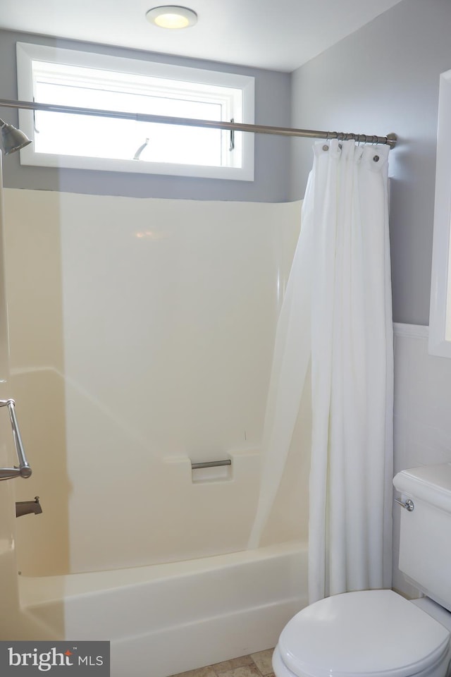 bathroom featuring shower / bath combo, toilet, and a wealth of natural light