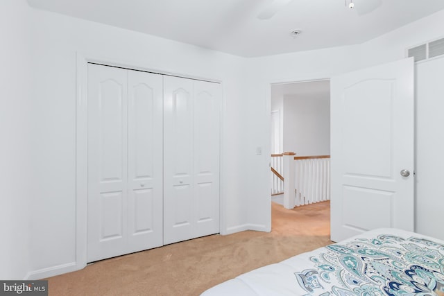 bedroom featuring a closet, light colored carpet, and ceiling fan