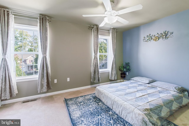 carpeted bedroom featuring multiple windows and ceiling fan