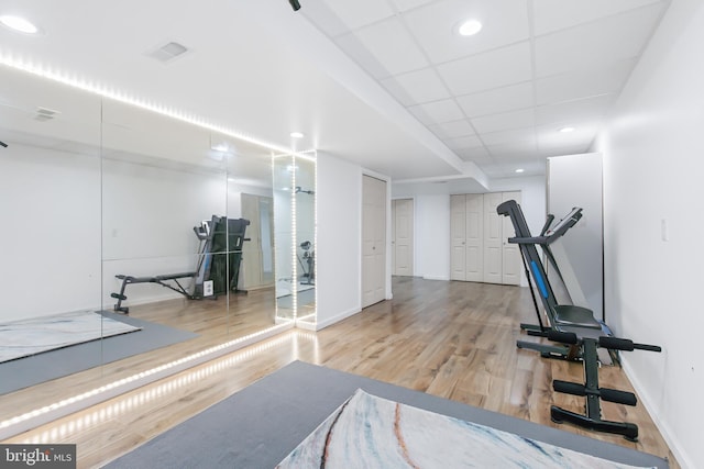 exercise area with hardwood / wood-style floors and a paneled ceiling