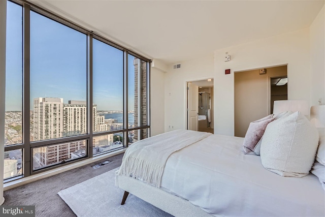 bedroom with carpet floors, a water view, a wall of windows, and multiple windows