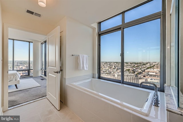 bathroom with a relaxing tiled tub and tile patterned flooring