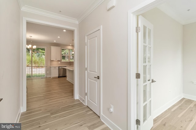 hallway with light hardwood / wood-style floors, ornamental molding, and a chandelier