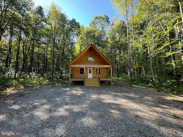view of outdoor structure featuring a porch and a wooded view