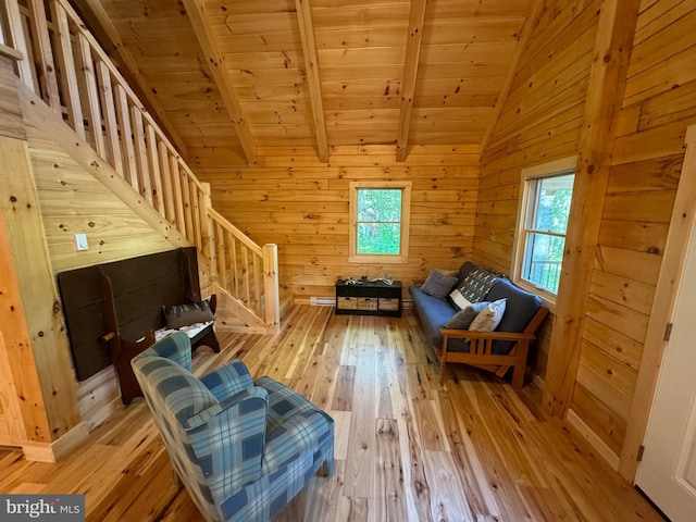 unfurnished room featuring wooden walls, stairs, light wood-style floors, vaulted ceiling with beams, and wooden ceiling