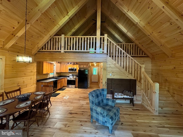 interior space with wood walls, beamed ceiling, light wood finished floors, stairs, and wood ceiling