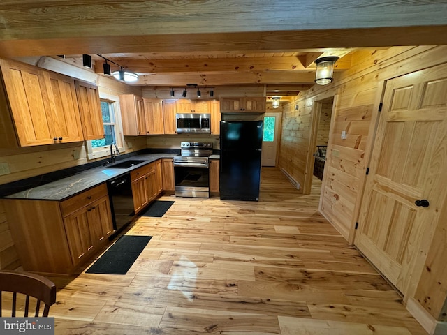 kitchen with light wood-style flooring, wood walls, beamed ceiling, a sink, and black appliances
