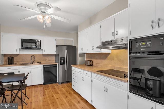 kitchen featuring light hardwood / wood-style floors, sink, white cabinetry, black appliances, and ceiling fan