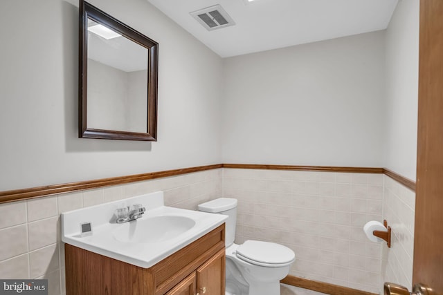 bathroom with vanity, tile walls, and toilet