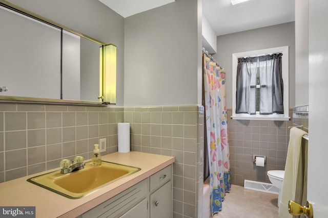 full bathroom with vanity, tile walls, shower / bath combo with shower curtain, and toilet