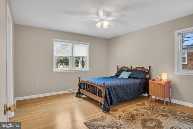 bedroom with ceiling fan, light hardwood / wood-style floors, and multiple windows