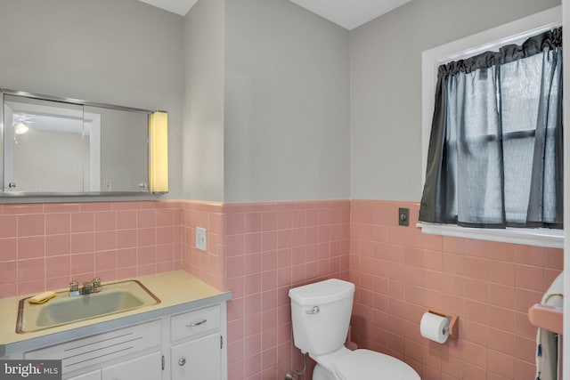 bathroom featuring tile walls, vanity, toilet, and a wealth of natural light