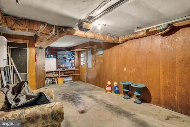 basement featuring electric panel and wooden walls