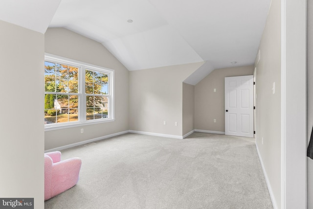 additional living space featuring vaulted ceiling and light colored carpet