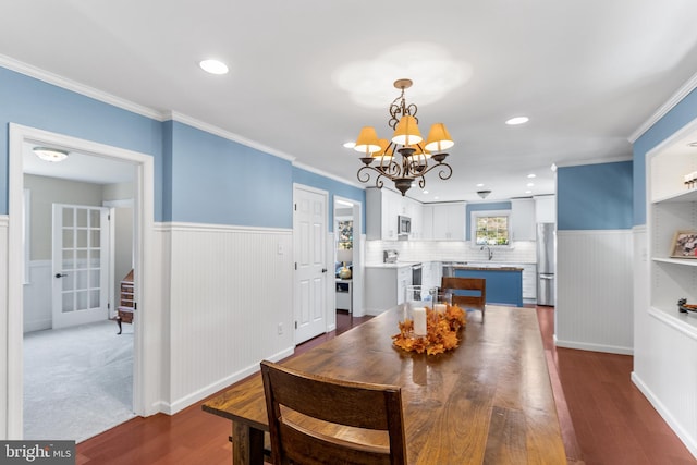 dining space featuring a notable chandelier, sink, crown molding, and dark hardwood / wood-style flooring