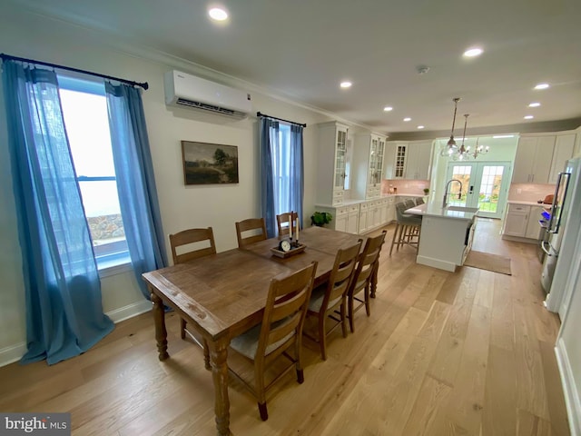 dining room with a notable chandelier, a wealth of natural light, light hardwood / wood-style floors, and a wall unit AC