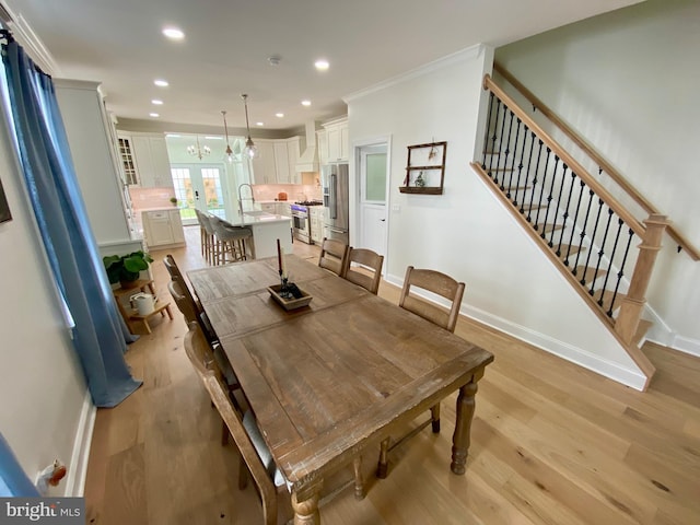 dining space with ornamental molding, sink, and light hardwood / wood-style flooring