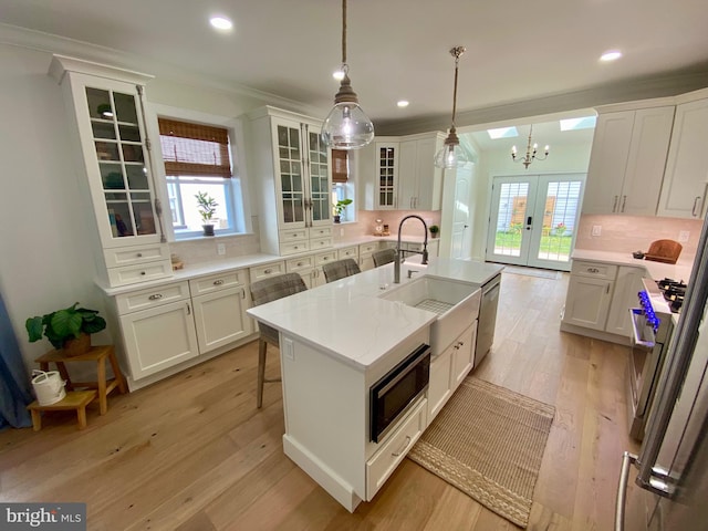 kitchen featuring backsplash, decorative light fixtures, plenty of natural light, and white cabinets