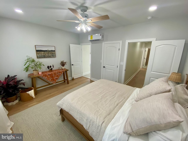 bedroom featuring ceiling fan, light hardwood / wood-style flooring, and a wall mounted AC