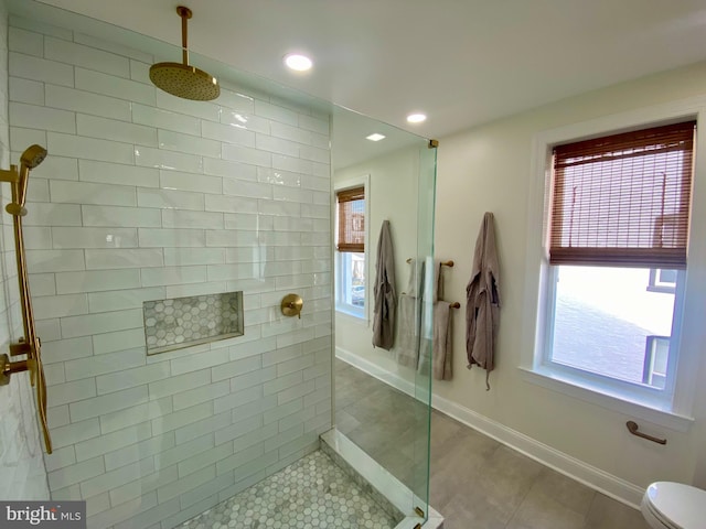 bathroom with toilet, tile patterned flooring, and a tile shower