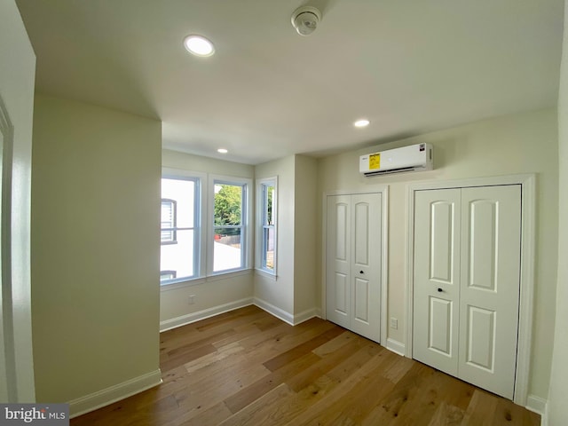 interior space with light hardwood / wood-style flooring and a wall unit AC