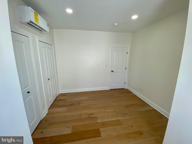 unfurnished room featuring light hardwood / wood-style floors and a wall mounted air conditioner